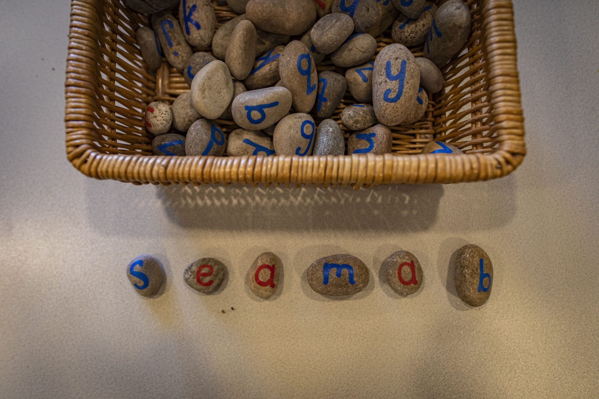 Basket of pebbles with letters painting on them spelling out Seamab.